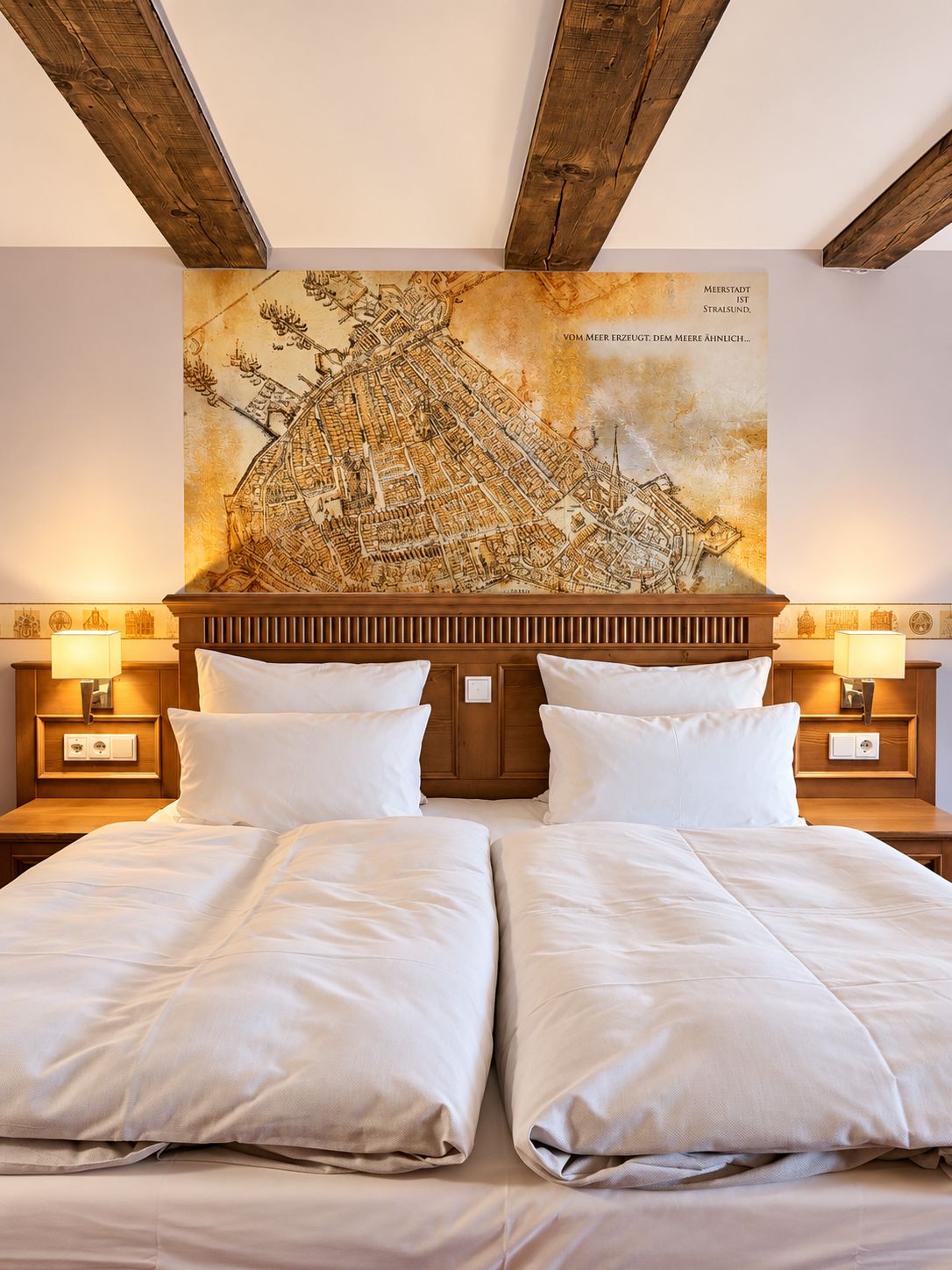 Ein Doppelbett mit Holzvorhang, zwei Nachttische mit Lampen und eine große Stadtkarte an der Wand.