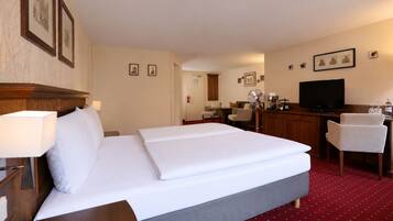 Une chambre d’hôtel avec un lit double, un bureau avec une chaise, une télévision et un petit coin cuisine.