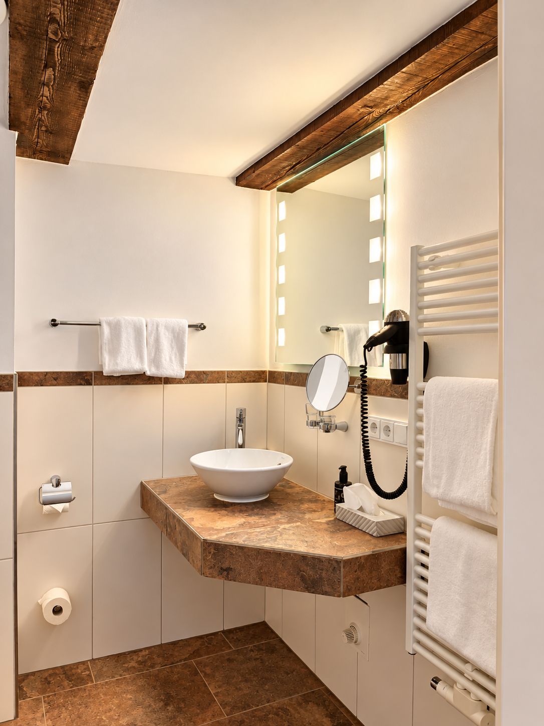 Ein Badezimmer mit Holzboden, einem weißen Waschbecken, einem Spiegel, einem Handtuchhalter und einer Handtuchheizung.