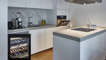 Una cocina moderna con un refrigerador para vinos empotrado, una cafetera y una isla elegante con lavamanos.