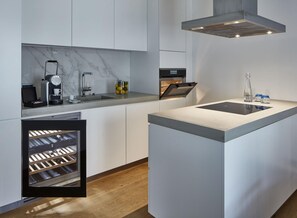 Una cocina moderna con un refrigerador para vinos empotrado, una cafetera y una isla elegante con lavamanos.