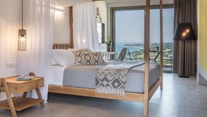 A four-poster bed with a view of the sea, a bedside table with a book, and a lamp. - Asteris Hotel (Kefalonia)