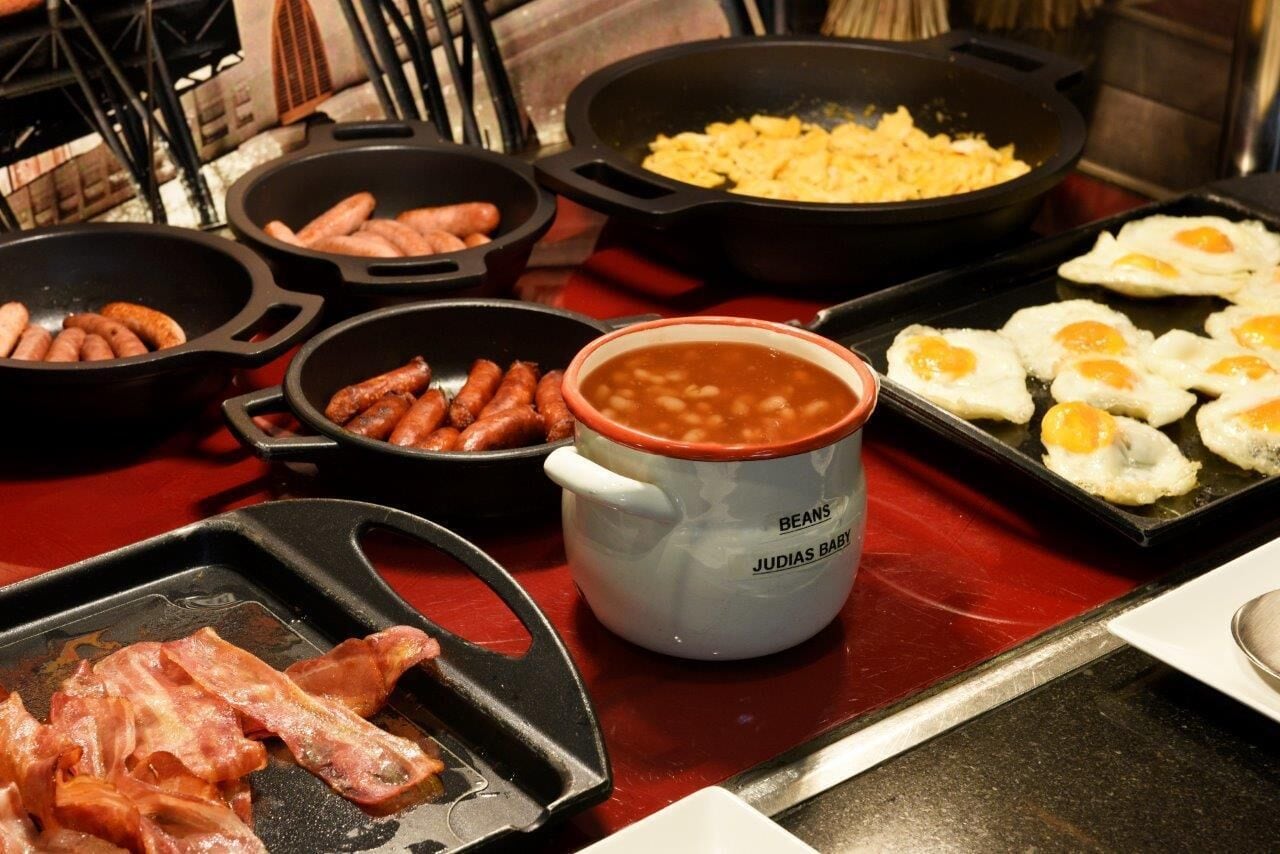 Colazione con salsicce, pancetta, uova e fagioli.
