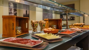 Un buffet proposant une variété de plats, notamment des viandes, des fromages et du pain.