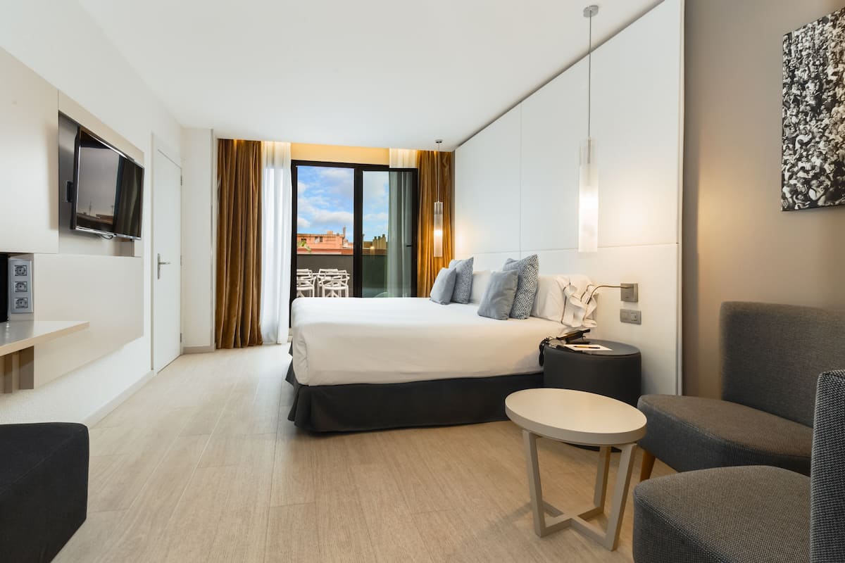 Una habitación de hotel moderna con cama, televisor, escritorio y silla.