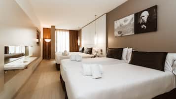 A hotel room with two beds, a desk, a mirror, and a large window with curtains.