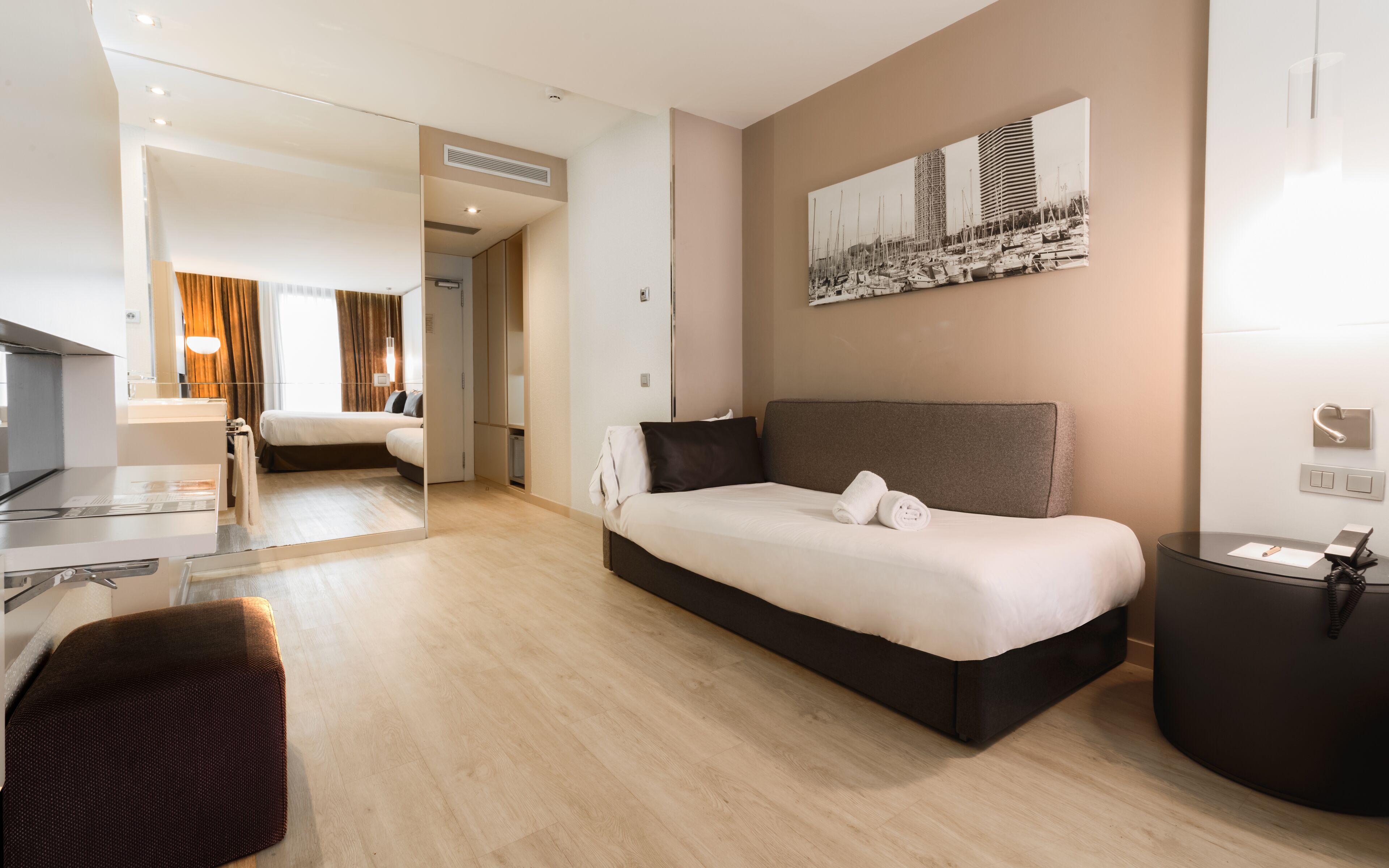 A modern hotel room with a large bed, a desk, and a seating area.