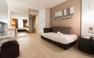 A modern hotel room with a large bed, a desk, and a seating area.