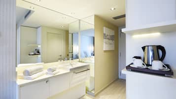 Une salle de bain moderne avec un grand miroir, deux vasques et un plateau avec du café et des tasses.