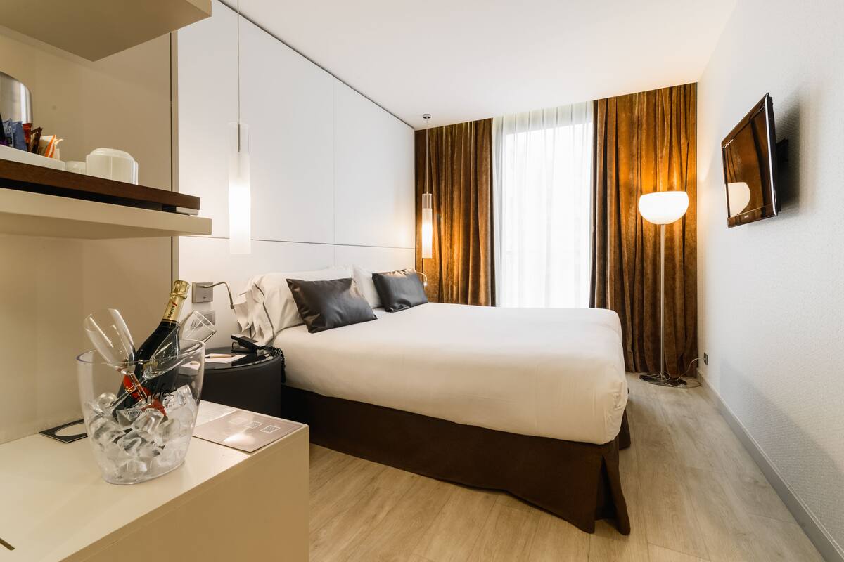 Una habitación de hotel moderna con cama, mesita de noche y minibar.