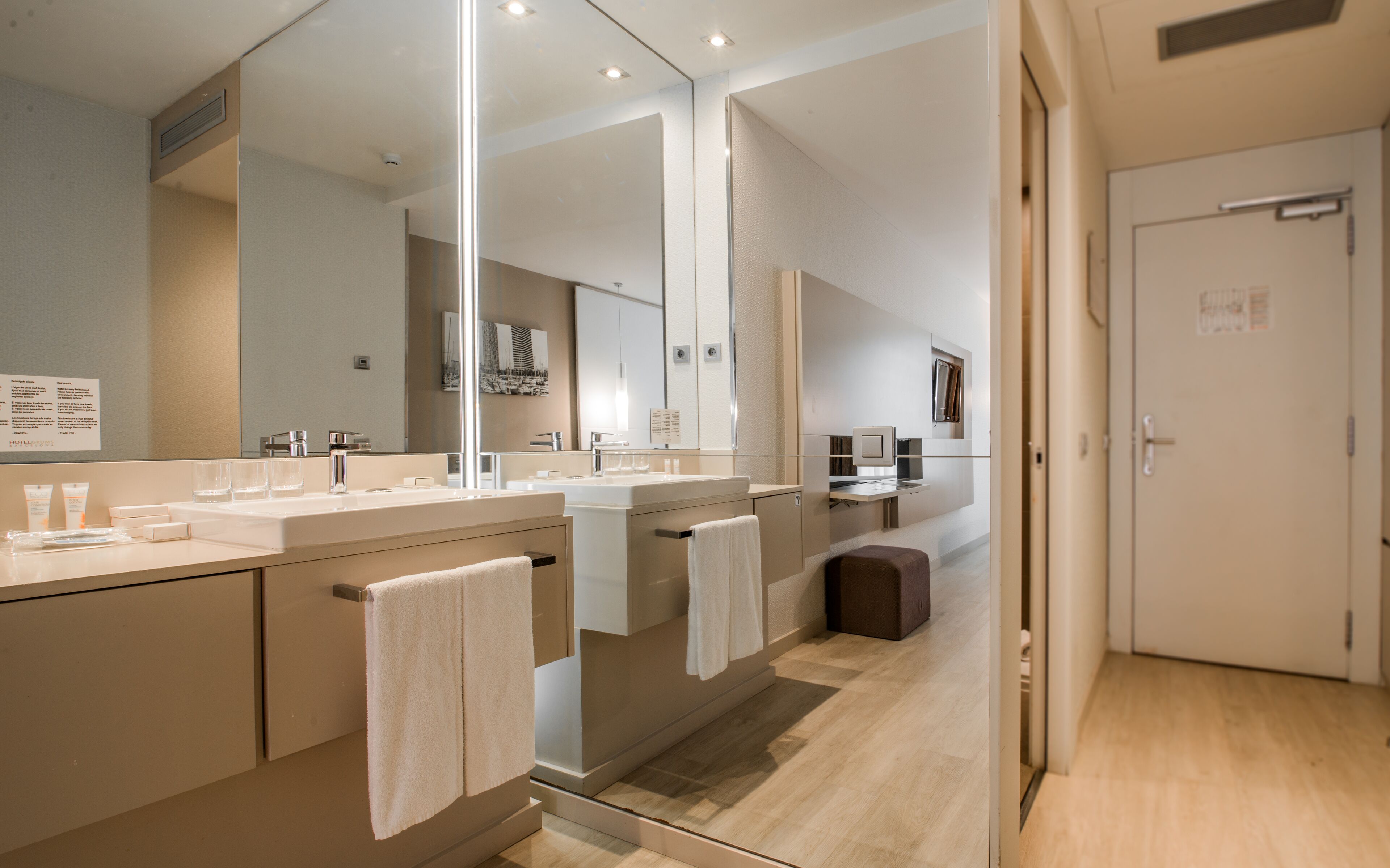 Un bany modern amb un mirall gran, un lavabo i un vàter.