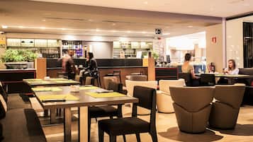 A modern restaurant with multiple seating areas, including tables and booths, and a bar area with a variety of beverages and glasses.