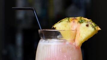 A glass with a straw and a slice of pineapple on the rim, placed on a wooden surface.