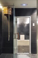 A modern bathroom with a glass door, a wooden barrel, and a towel rack.