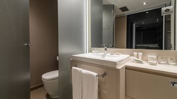 A modern bathroom with a white sink, mirror, and toilet.