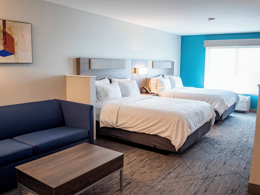 A hotel room with a bed, a sofa, a coffee table, and a painting on the wall.