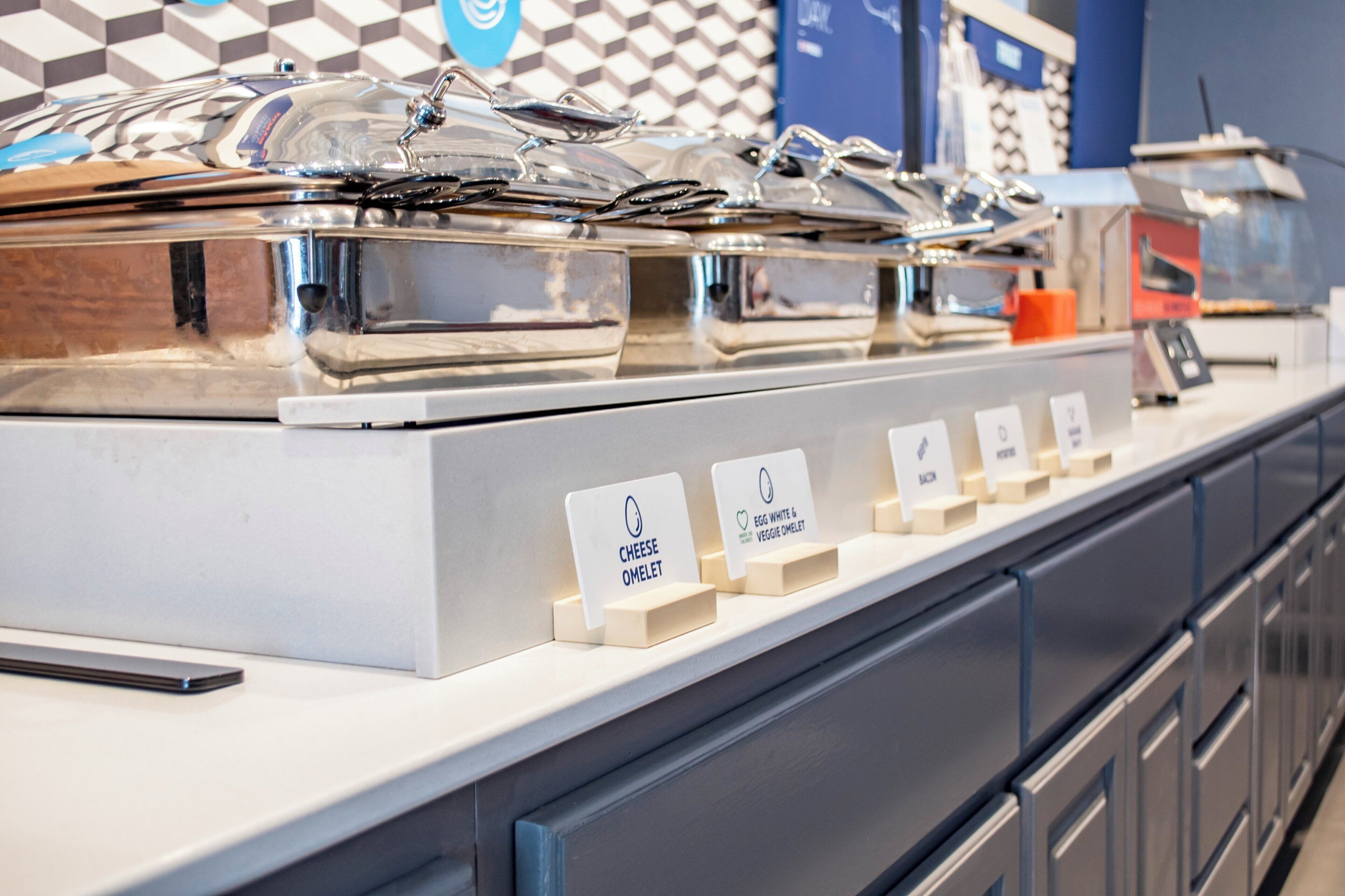 A breakfast buffet with labeled sections for cheese omelet and egg white & veggie omelet.