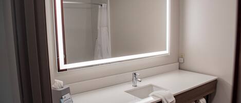 A bathroom with a large mirror, a sink, and a towel rack.