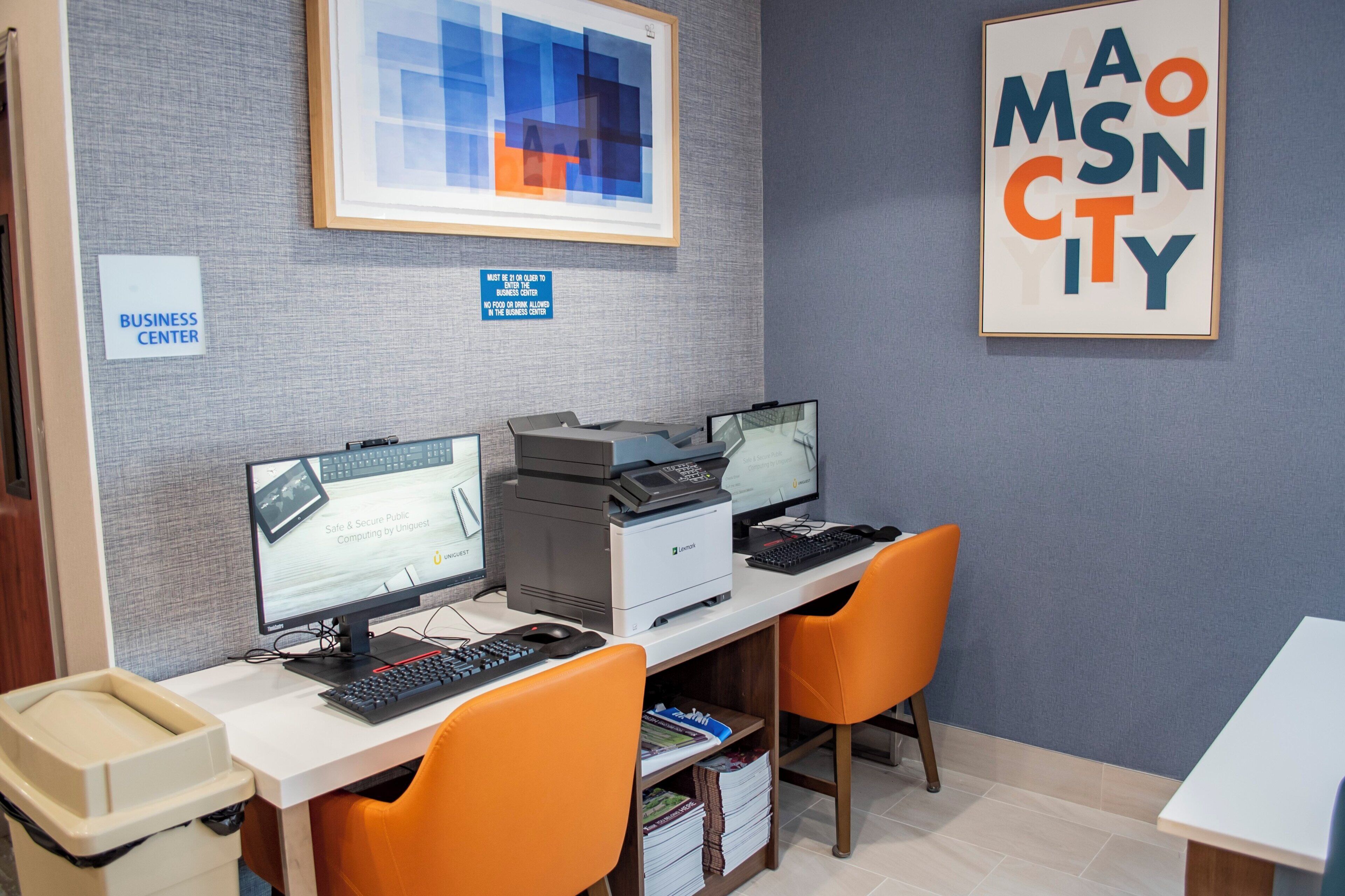 A business center with multiple computer stations, chairs, and a printer.