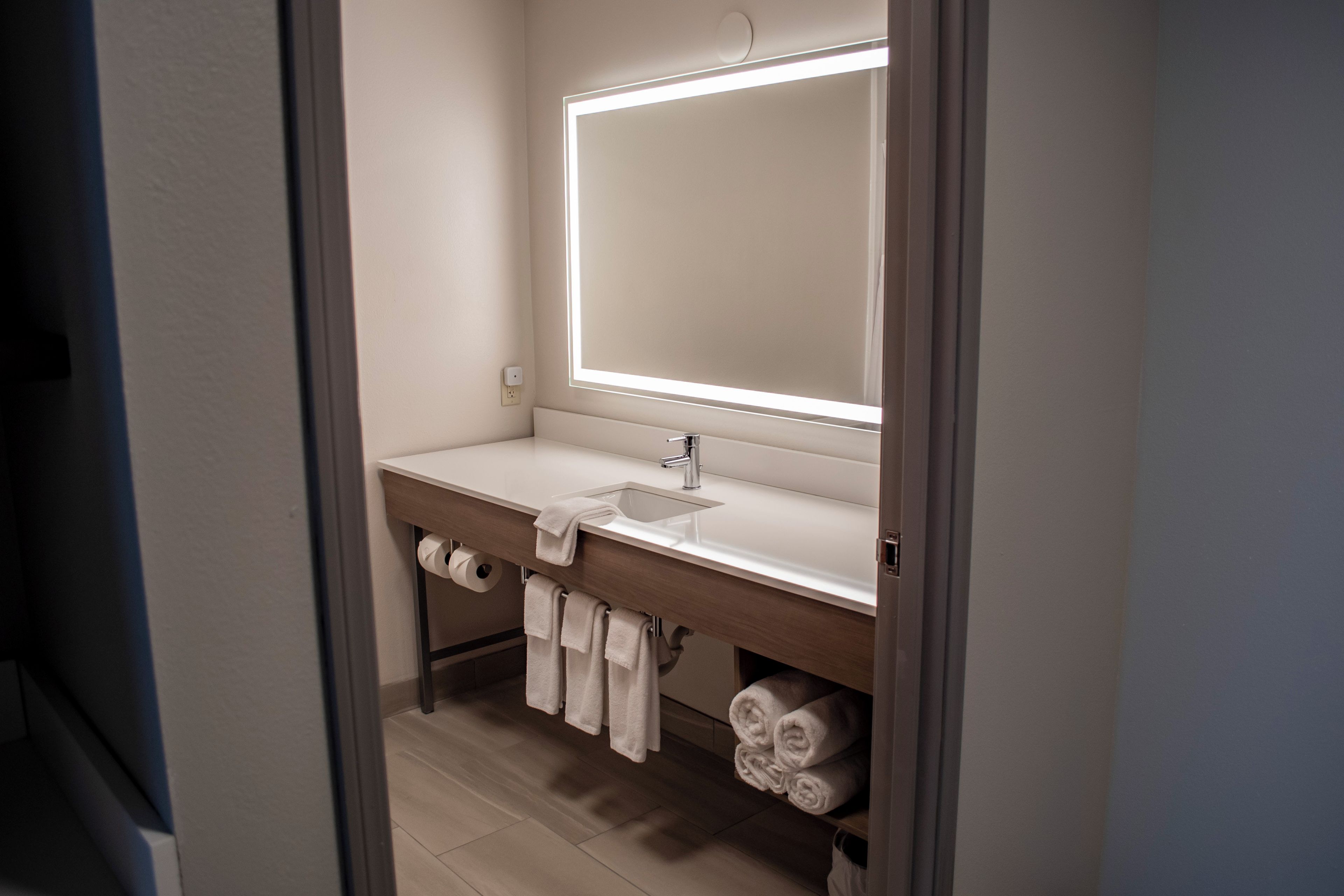 Un baño moderno con un espejo grande, un lavamanos y un perchero para toallas.