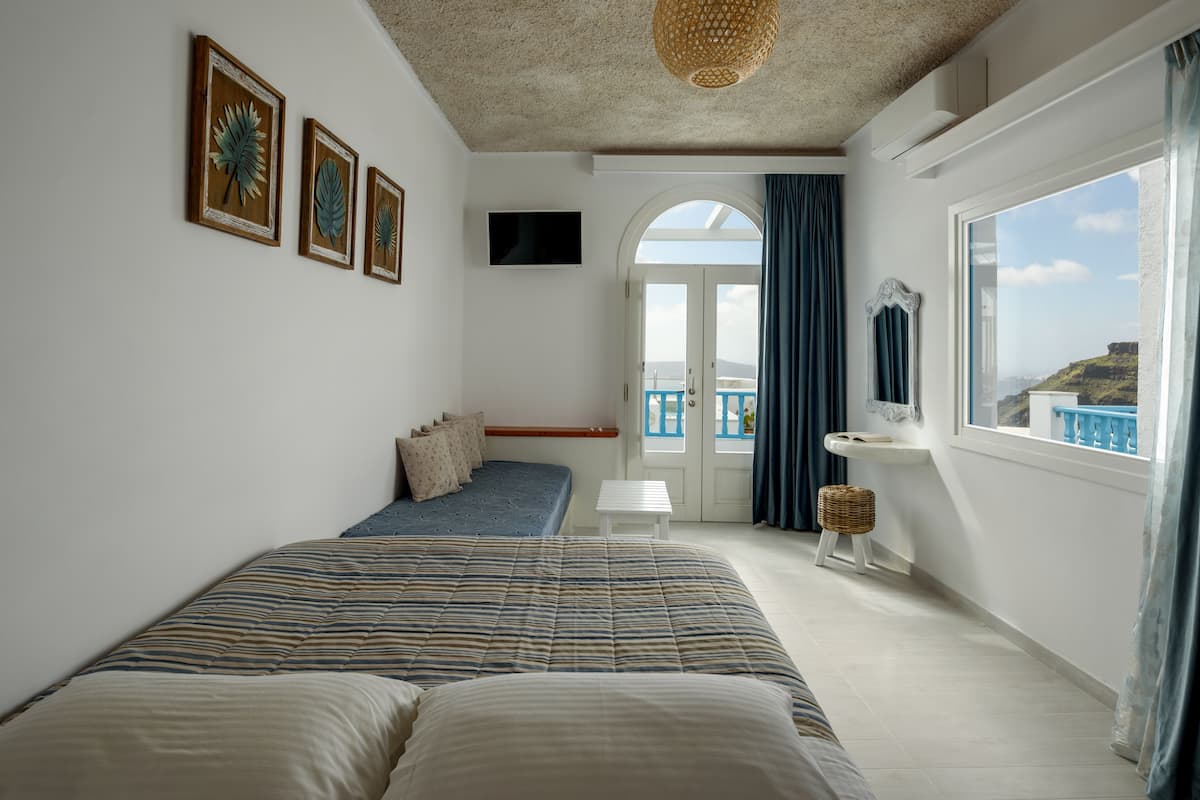 Une chambre avec un lit, une petite table, un lavabo et une vue sur la mer.