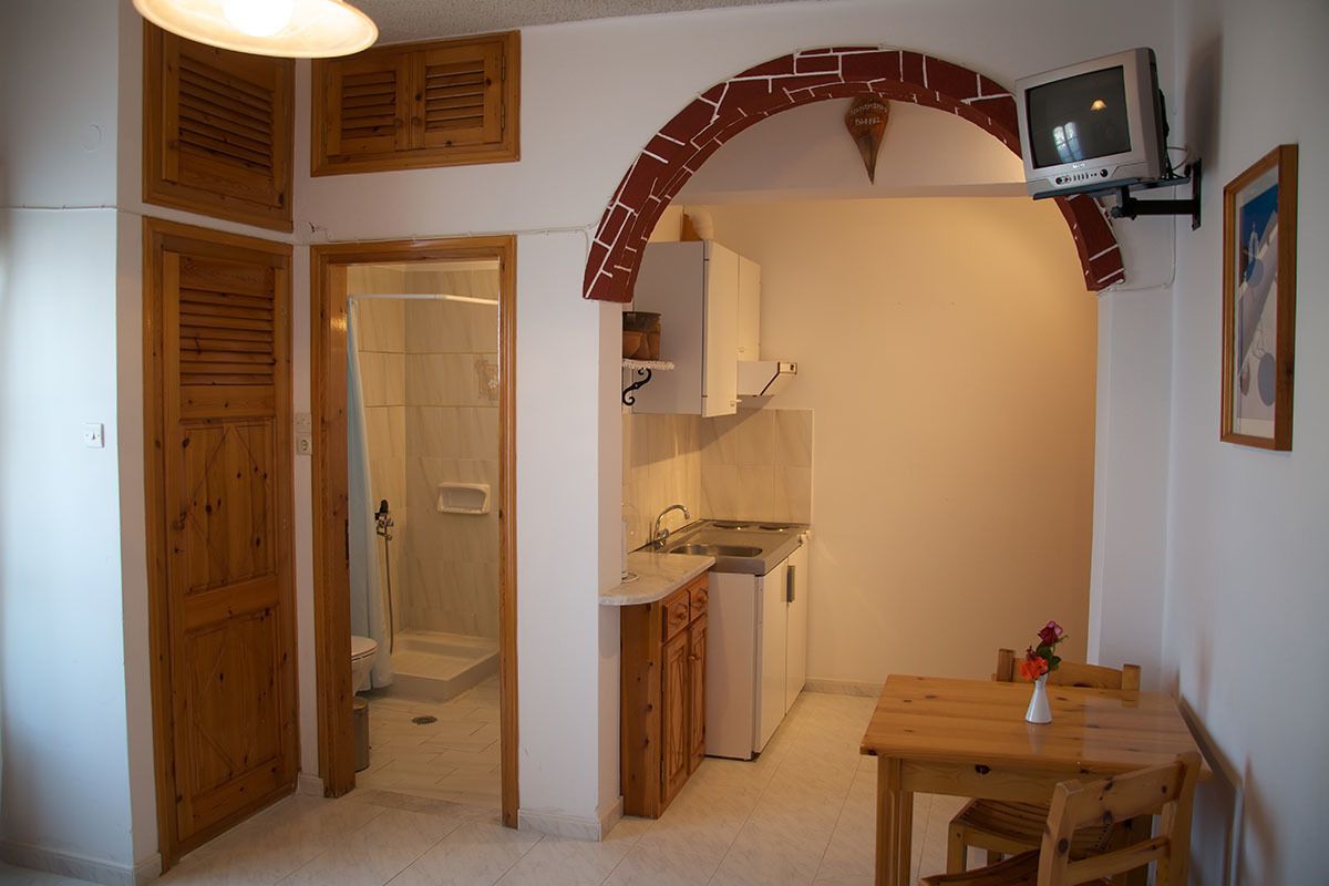 A compact kitchen with a built-in oven, a sink, and a small dining table.