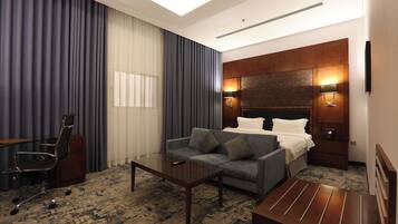 A hotel room with a sofa, a coffee table, a desk, and a bed.