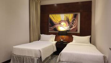 A hotel room with two beds, a nightstand, a lamp, and a large abstract painting on the wall.