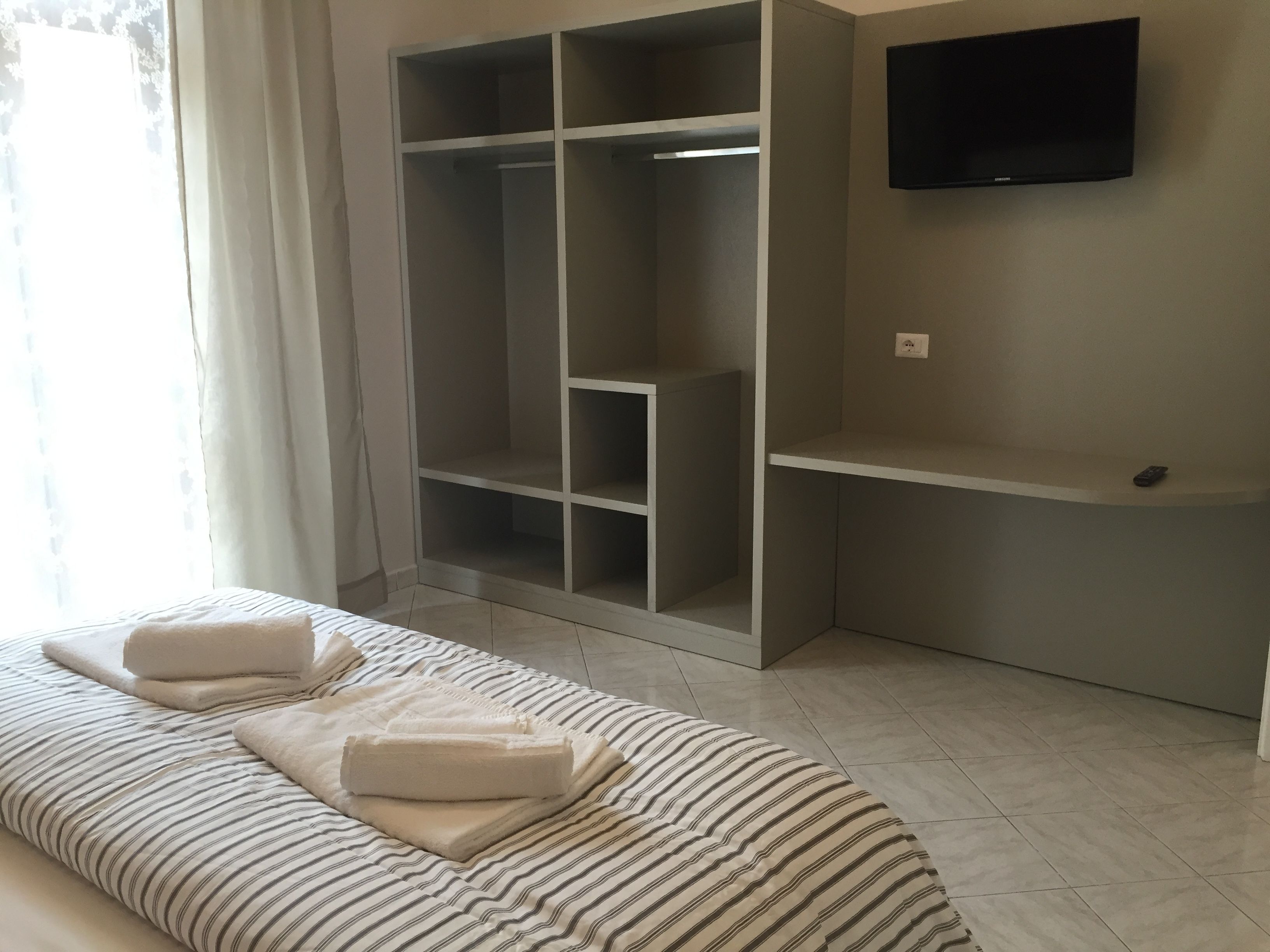 A bedroom with a bed, a wardrobe, and a TV.