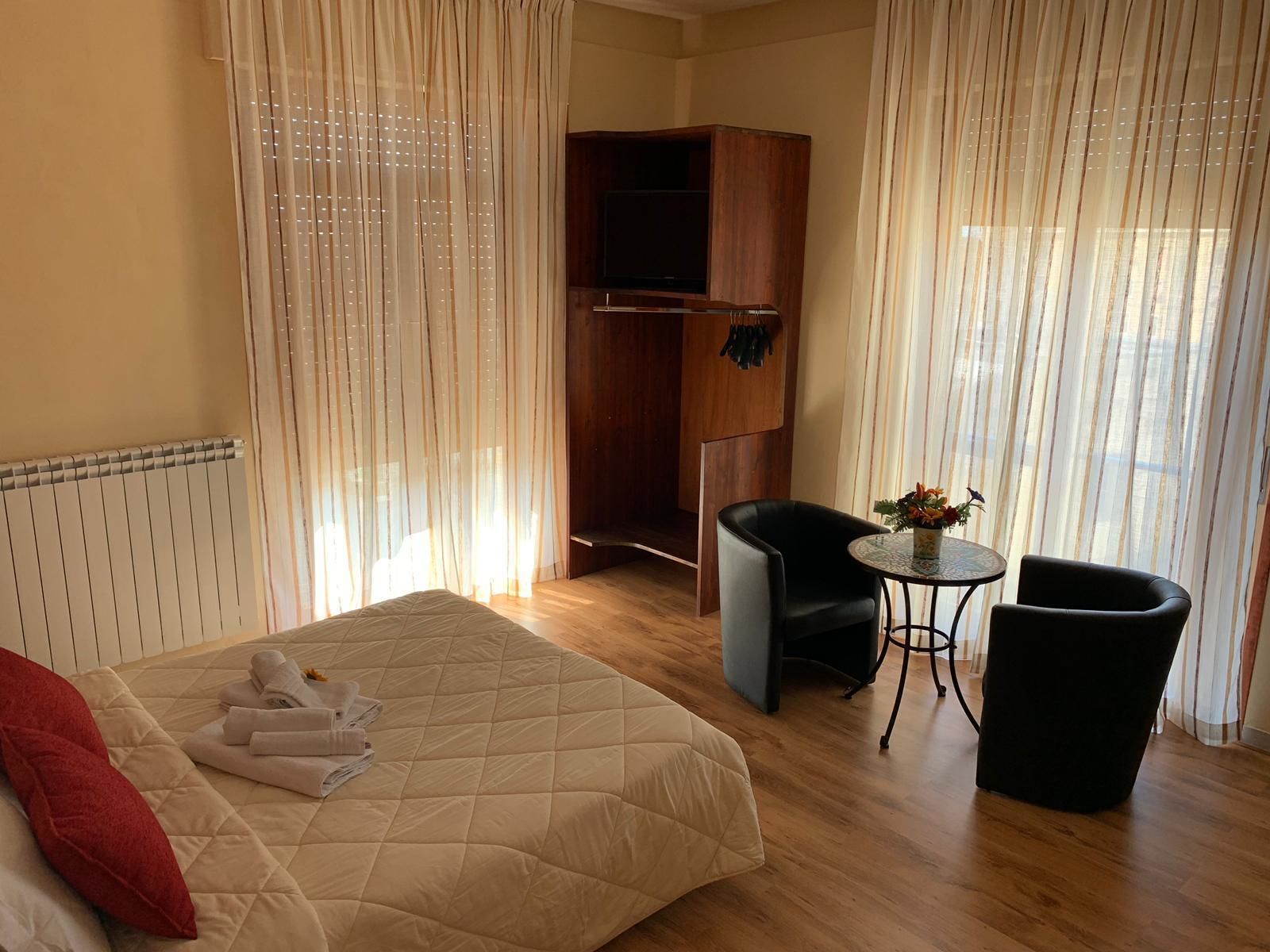 Quarto de hotel com cama, escrivaninha, cadeira e guarda-roupa.