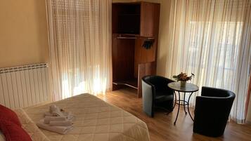 Quarto de hotel com cama, escrivaninha, cadeira e guarda-roupa.