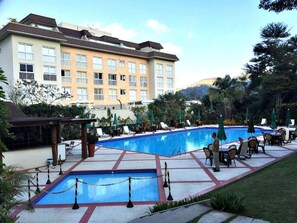Un hôtel doté d’une piscine, d’un espace extérieur aménagé et d’un bâtiment avec de nombreuses fenêtres.