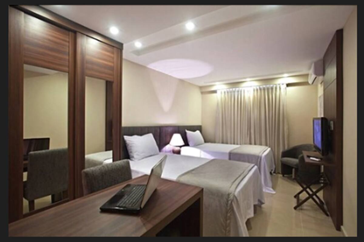 Ein Hotelzimmer mit zwei Betten, einem Schreibtisch mit Laptop, einem Fernseher und einer Sitzecke.
