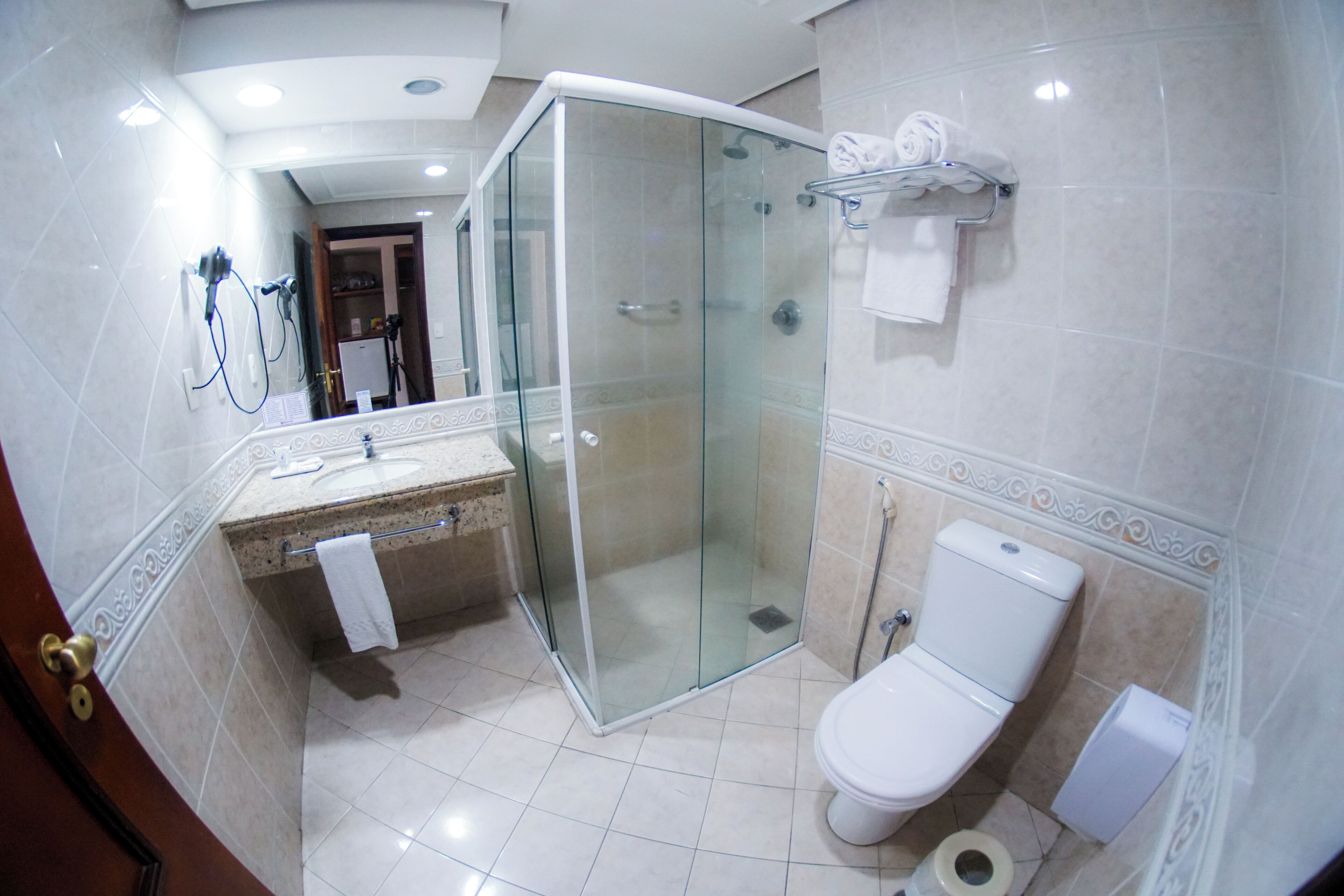 A modern bathroom with a glass-enclosed shower, a white toilet, and a vanity with a towel hanging on the wall.