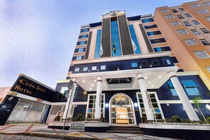 A modern hotel with a prominent entrance, large windows, and a flagpole.