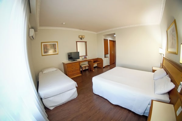 A hotel room with two beds, a desk with a chair, a television, and a mirror.