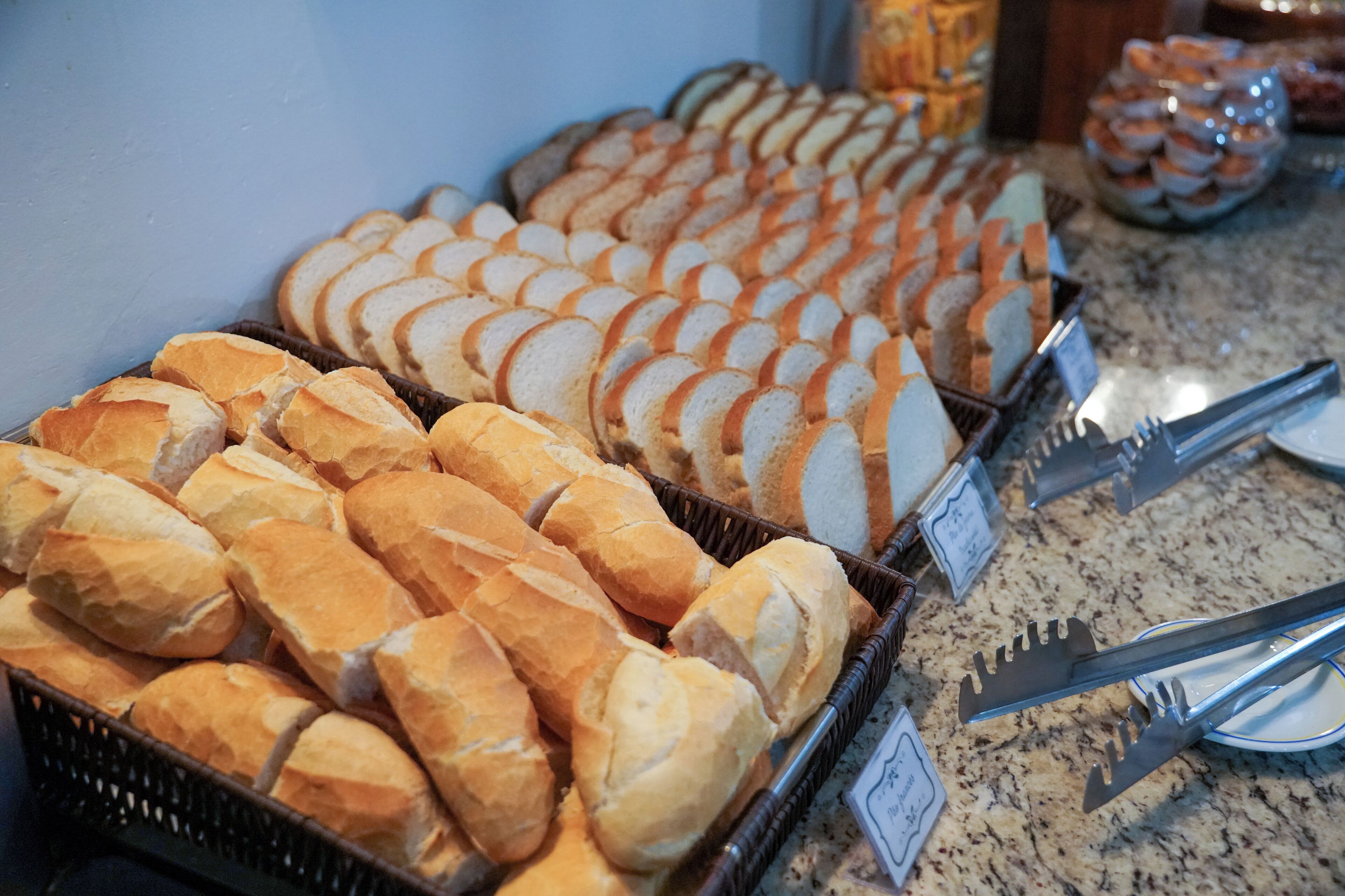 A buffet with various types of bread and a sign indicating the price.