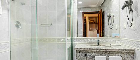 A modern bathroom with a glass-enclosed shower, a marble sink, and a large mirror.