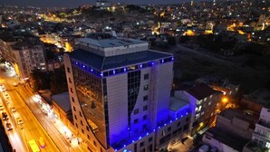 A hotel with a modern glass facade, located at a city intersection with visible traffic. - Ravanda Hotel (Gaziantep)