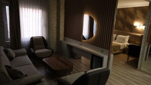 A hotel room with a sofa, armchair, coffee table, and a bed with a headboard. - Ravanda Hotel (Gaziantep)