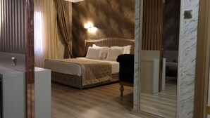 A bedroom with a bed, bedside table, and a mirror. - Ravanda Hotel (Gaziantep)