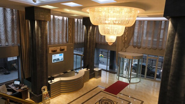 A hotel lobby with a reception desk, a large chandelier, and a revolving door. - Ravanda Hotel (Gaziantep)