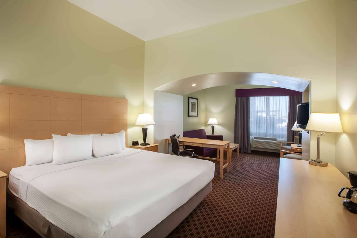 Een hotelkamer met een groot bed, een bureau, een stoel en een televisie.