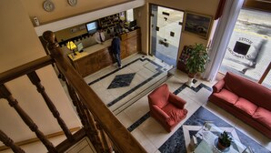 A hotel lobby with a reception desk, a red sofa, a coffee table, and a potted plant. - Hotel Internacional (Buenos Aires)