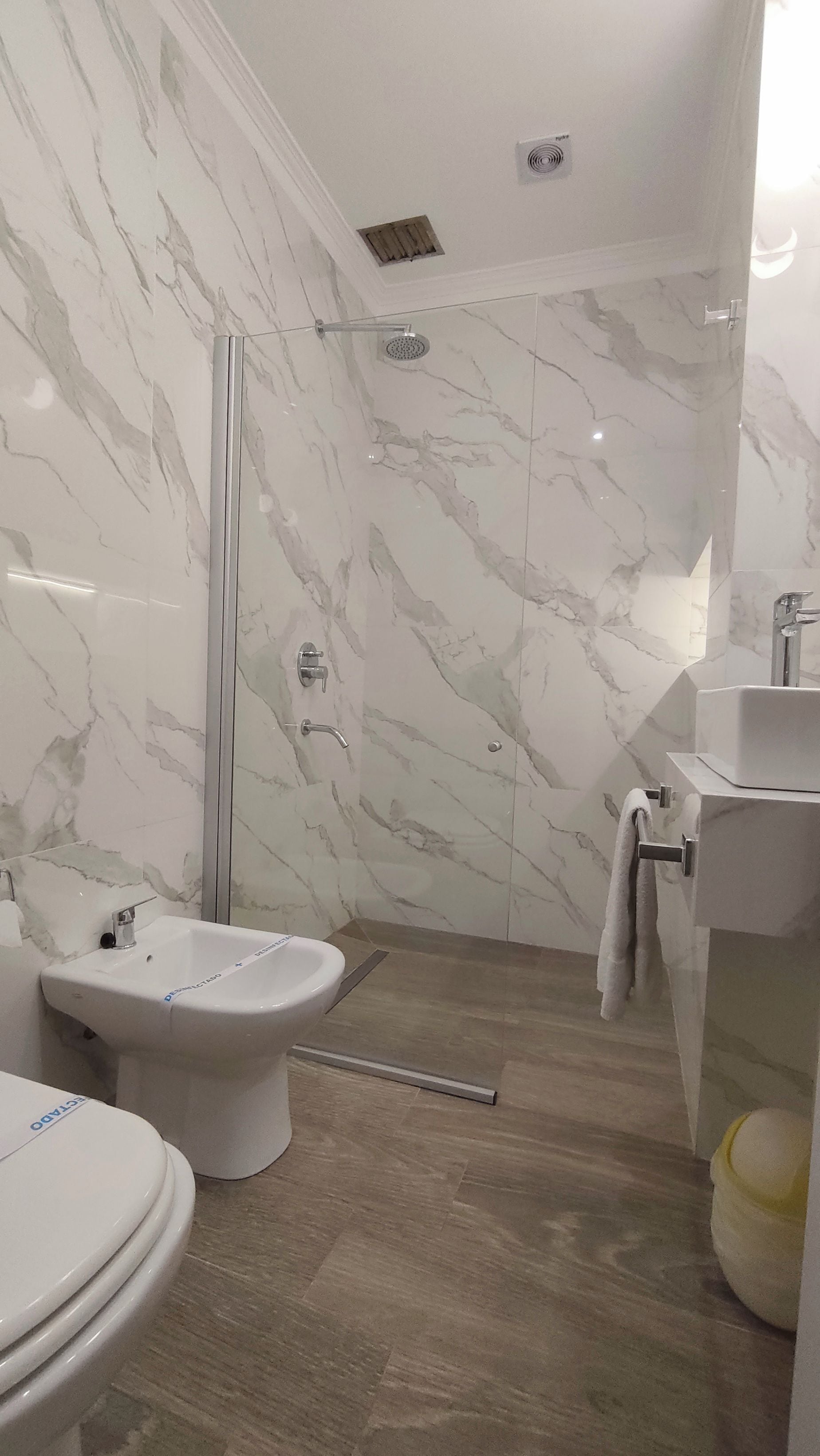A bathroom with a shower, toilet, bidet, and sink.