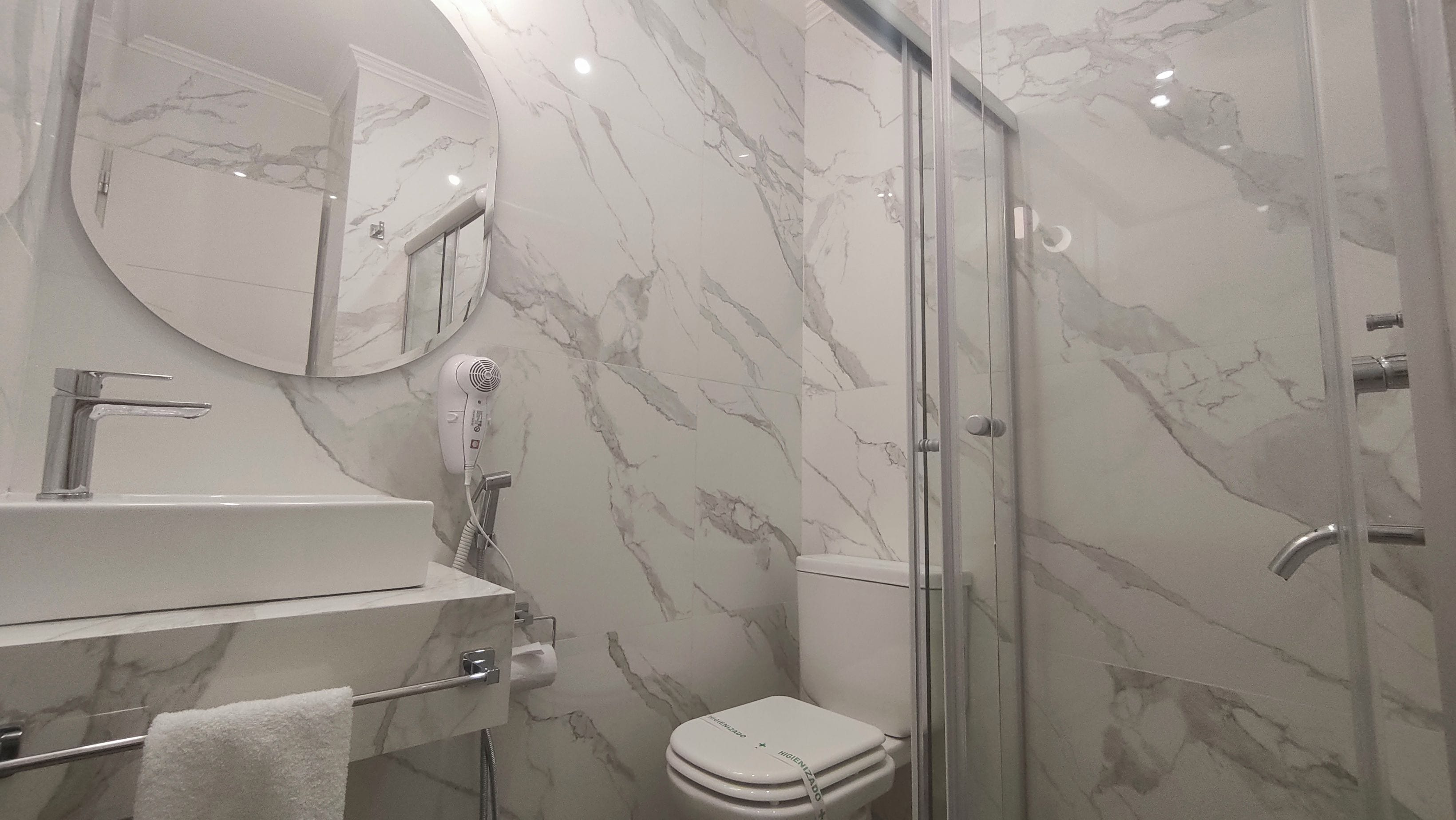 A bathroom with a marble sink, a toilet, and a glass shower enclosure.