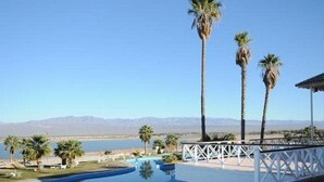 A resort with a pool, palm trees, and a view of mountains. - Del Bono Beach (San Juan)
