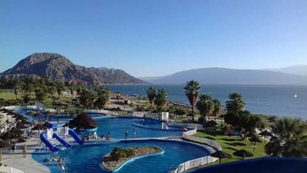 A resort with multiple swimming pools, a water slide, and a view of the ocean and mountains. - Del Bono Beach (San Juan)