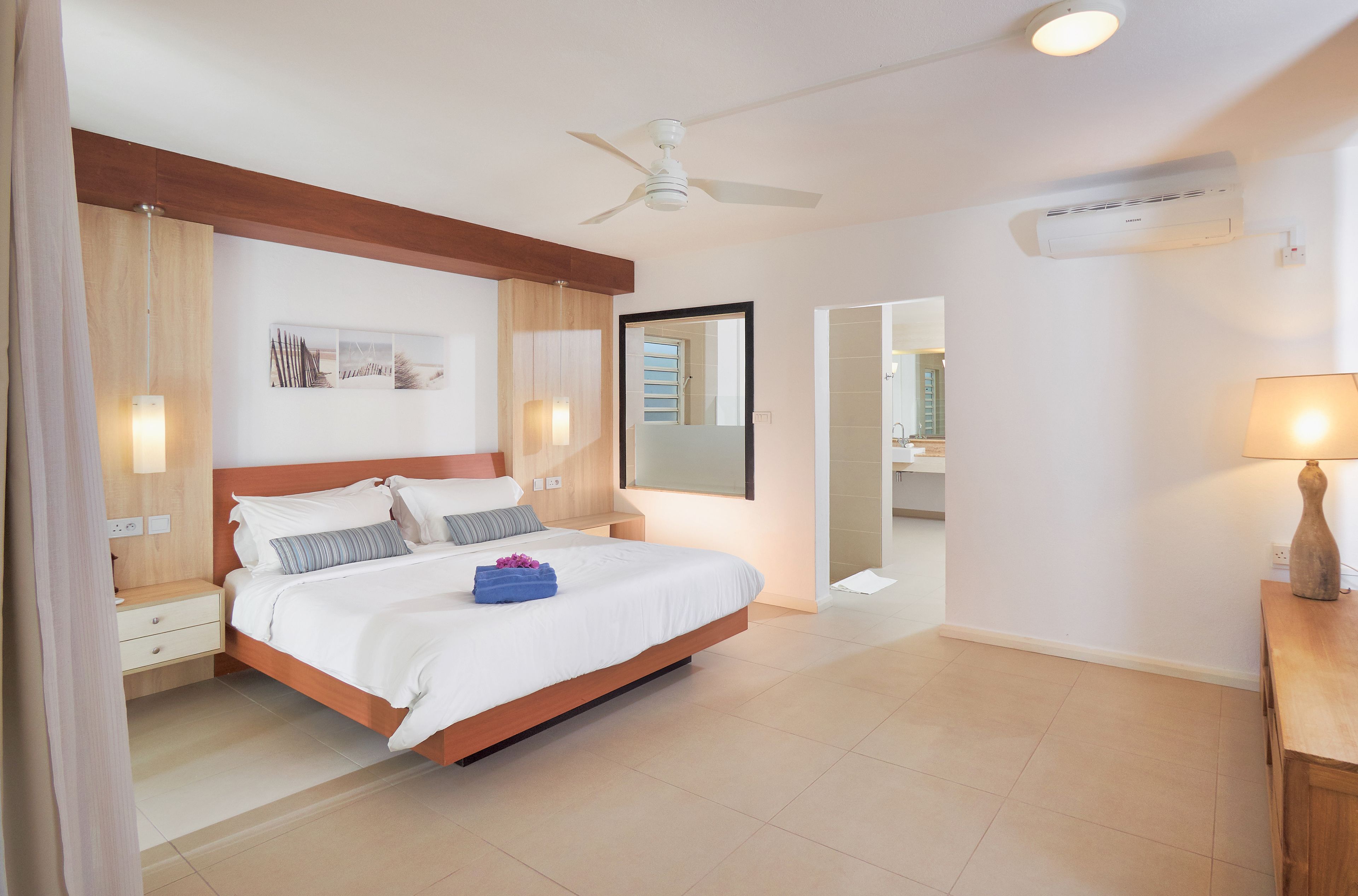 Ein modernes Schlafzimmer mit einem Bett, Nachttischen, einem Deckenventilator und einer Klimaanlage.
