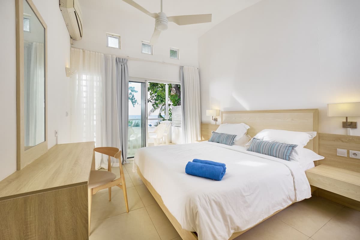 A hotel room with a bed, a desk, a chair, and a balcony with a view.